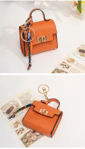 Detail of orange mini bag keychain with lychee leather texture and silk ribbon scarf