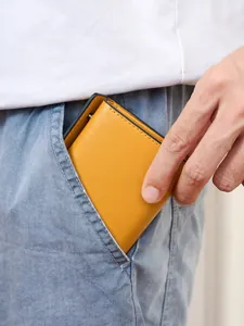 Slanke gele herenportefeuille van microvezelleer getoond in een blauwe spijkerbroekzak