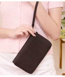 Detail of dark brown RFID passport wallet featuring wrist strap and stitching texture