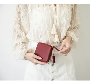 Detail of red leather square wallet featuring a zip closure and stylish long tassel charm