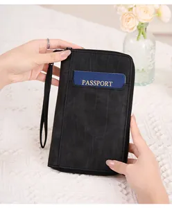 Détail du protège-passeport RFID noir avec texture marbre et dragonne sur table blanche