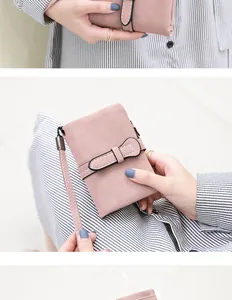 Detailed view of pink PU leather wallet with bow clasp and wrist strap being held