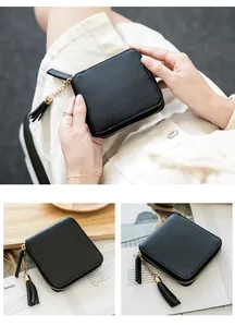 Close-up of black square zip wallet with smooth texture and decorative tassel charm