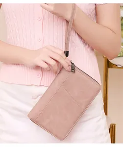 Pink RFID blocking passport wallet with wrist strap and front pocket in hand