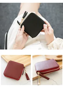 Close-up of stylish square zipper wallet featuring tassel charms and metal chain details