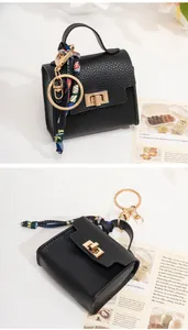 Close-up of black lychee leather mini bag charm with gold hardware and silk scarf detail
