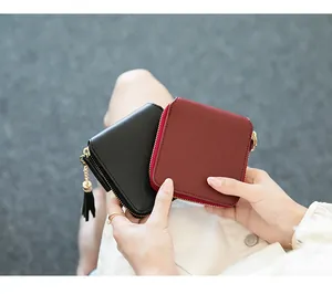 Detail of minimalist square zipper wallets in black and burgundy with tassel hardware
