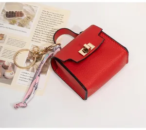 Macro detail of mini red leather bag keychain with silk scarf and gold twist lock