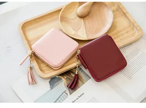 Close-up of square faux leather wallets with elegant tassels and gold zippers