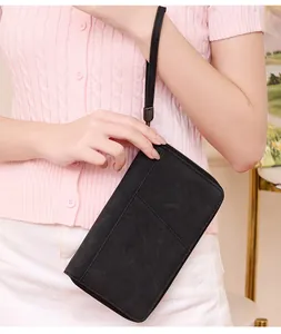 Detail view of black RFID passport wallet with wristlet held by a model on light background
