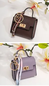 Macro detail of mini leather bag charms with lychee texture and silk scarf decoration