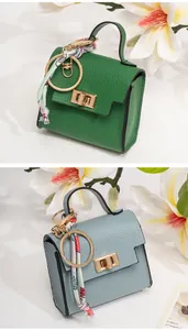 Detail of mini lychee leather handbag charm with gold lock and decorative silk scarf