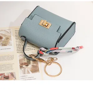 Close-up of a mini light blue leather bag keychain with golden lock and silk scarf detail
