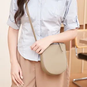 Détail du sac de selle taupe texture lychee avec fine bandoulière minimaliste