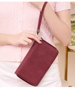 Burgundy RFID travel wallet in matte leather shown held by model with wrist strap