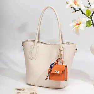 White pebbled leather tote bag with a mini orange bag charm and floral silk scarf detail