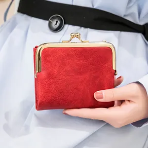 Vintage red leather mini wallet with gold metal clasp closure held by a female model