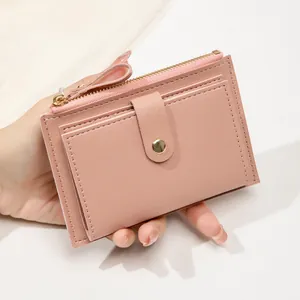 Détail d'un portefeuille en cuir rose avec fentes pour cartes et un bouton-pression en métal doré