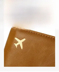 Detailed view of brown leather passport holder with golden airplane emblem and fine stitching
