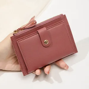 Gros plan du portefeuille rose poudré montrant le grain de cuir et le zip doré