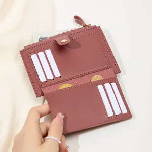 Gros plan d'un portefeuille rose montrant six fentes pour cartes et poche zippée