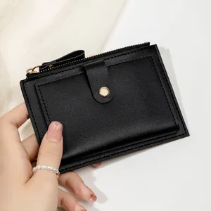 Détail d'un porte-cartes en cuir noir avec fermeture éclair dorée et bouton-pression