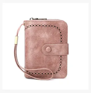 Detail of pink RFID wallet featuring laser-cut floral patterns and a gold metal wrist strap