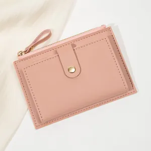 Gros plan du portefeuille en cuir grainé rose avec bouton pression doré et fermeture éclair