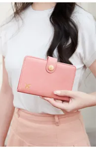 Detail of pink RFID passport holder with golden airplane logo and button closure