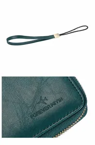 Detalle de cartera de viaje RFID en cuero verde oscuro con correa de mano extraíble