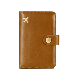Brown leather RFID blocking passport wallet with gold airplane accent and snap closure