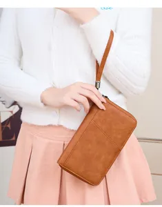 Portefeuille passeport RFID en cuir PU marron avec dragonne tenu par un mannequin