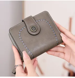 Vue détaillée du portefeuille en cuir gris avec motif cœur ajouré et bouton pression vintage