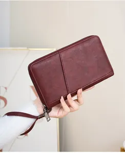 Gros plan du protège-passeport en cuir rouge foncé avec fermeture éclair et dragonne