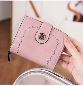 Détail du portefeuille rose clair avec design ajouré, boucle soleil et fermeture éclair