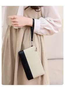 Détail d'une pochette bicolore en cuir PU avec dragonne et logo au design minimaliste