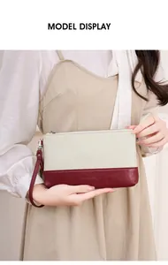 Mannequin tenant une pochette bicolore crème et bordeaux avec dragonne élégante