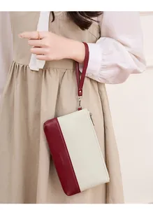 Détail de la pochette bicolore avec panneaux bordeaux et beige et dragonne amovible