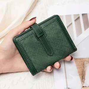 Détail d'un petit portefeuille vert foncé à carreaux avec surpiqûres blanches
