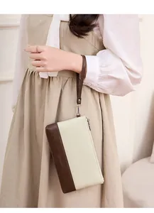Détail de la pochette bicolore en cuir avec fermeture éclair et dragonne amovible