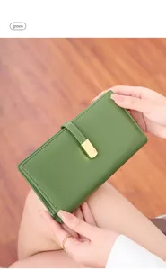 Detail view of avocado green leather wallet with gold buckle held by a model