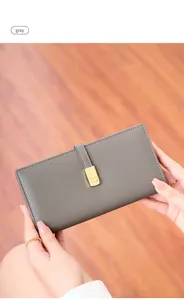 Detail of slim grey RFID women wallet with gold metal buckle on warm wood background