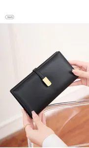 Detail of slim black RFID wallet with elegant gold buckle held by hand in a chic room