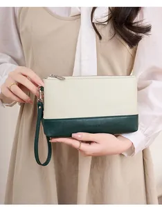 Détail de la pochette bicolore en cuir avec dragonne et logo gaufré élégant