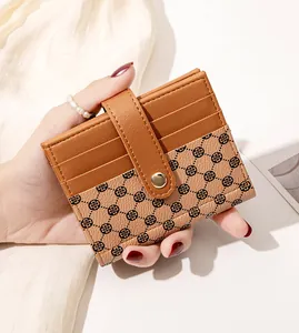 Detail of a brown leather card holder with clover print and snap button closure