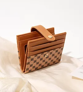 Detail of caramel leather card holder with clover pattern, multiple slots, and gold snap