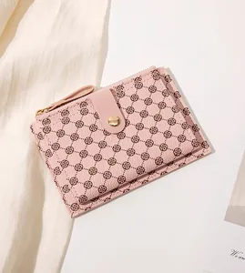 Close-up of pink faux leather wallet featuring a clover pattern and golden zipper details