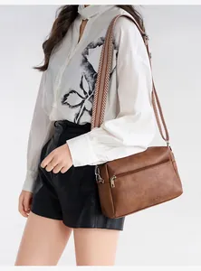 Close-up of brown soft leather crossbody bag with patterned wide strap and silver zipper