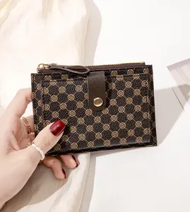 Close-up of slim floral card holder wallet with gold zipper and snap closure held by hand