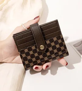 Detail of compact brown wallet with clover print, pebble leather texture and gold snap button